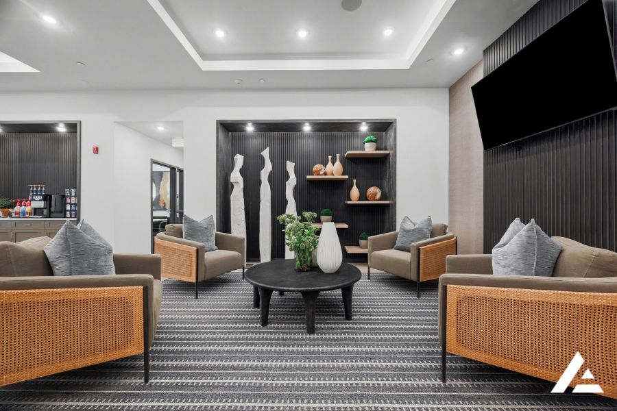 Modern lounge with four armchairs, a round table, decorative vases, and abstract art on the walls.