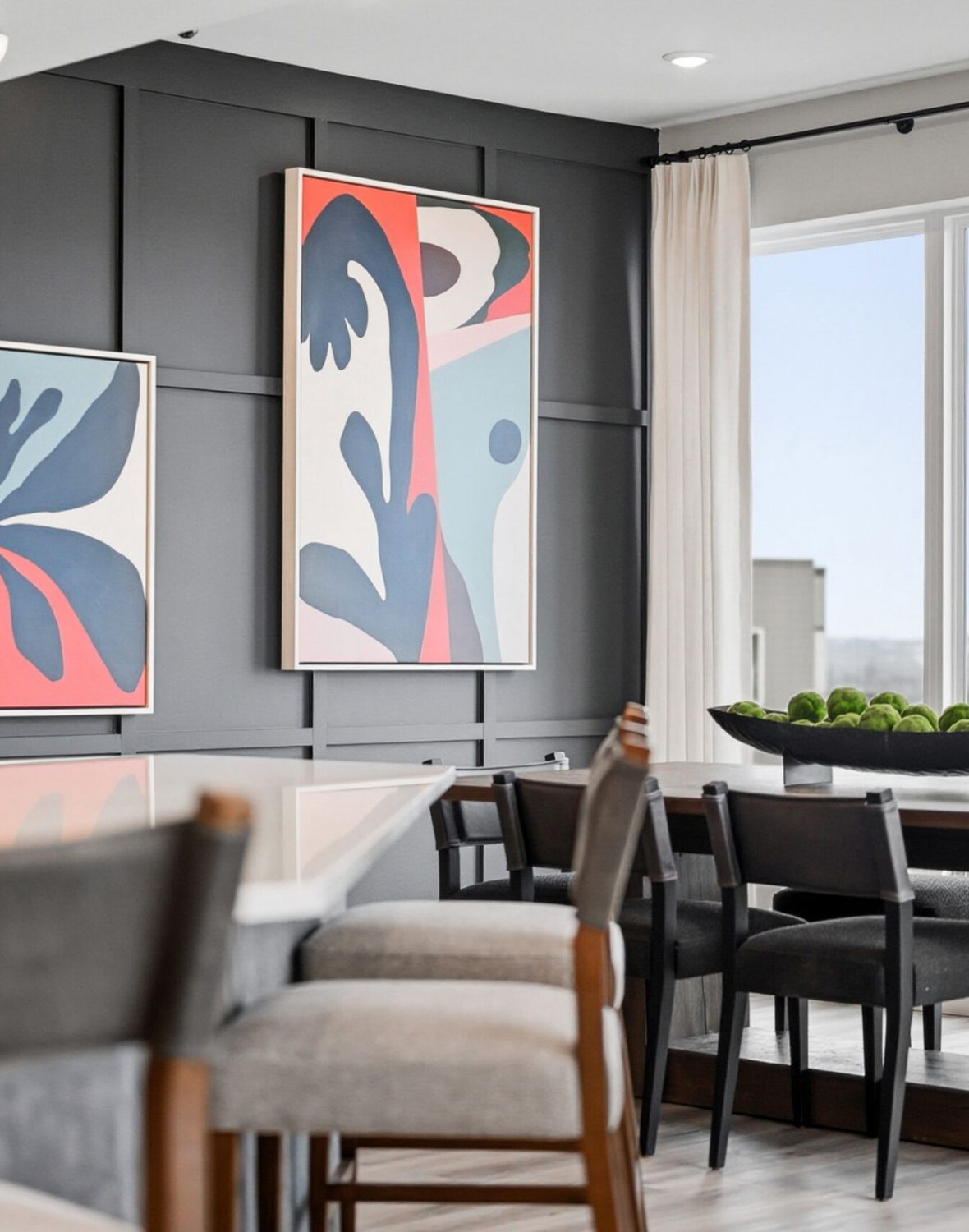 Modern dining area with abstract art, gray chairs, and large windows with sheer curtains.