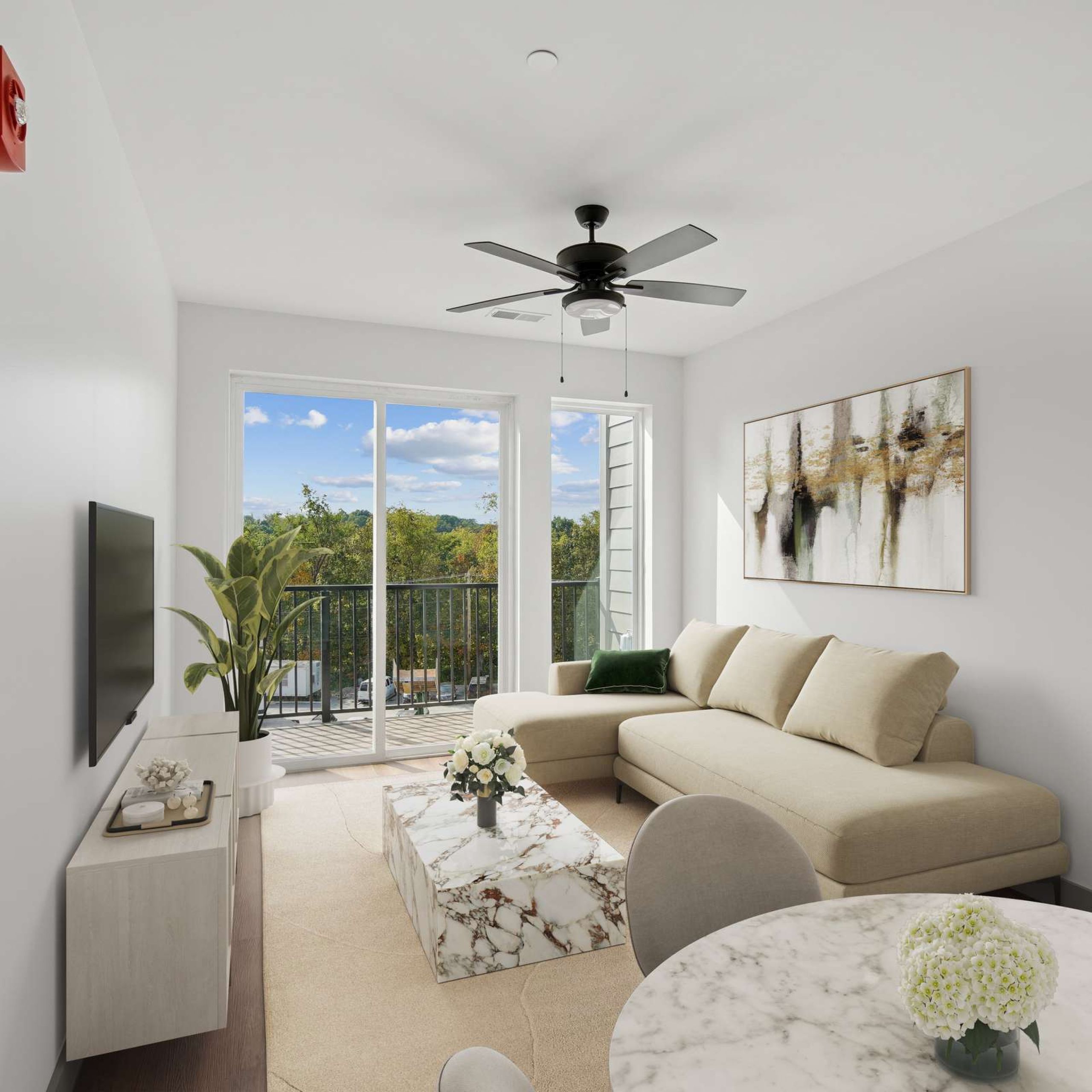 Bright living room with a beige sofa, marble coffee table, wall art, TV, and balcony view of trees.